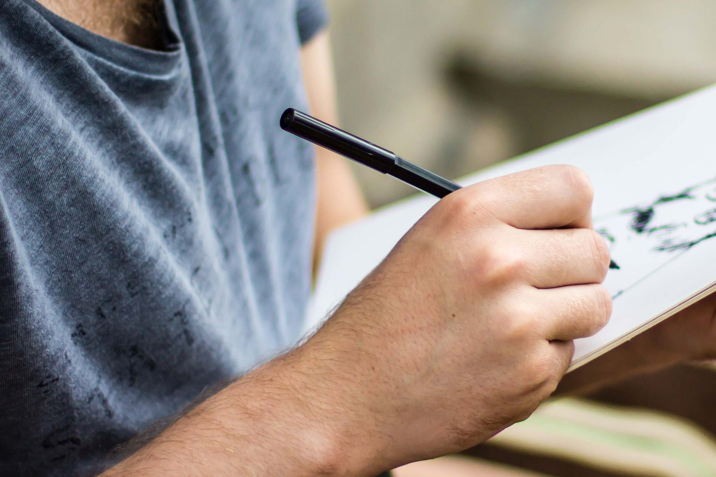 man drawing on paper with pen